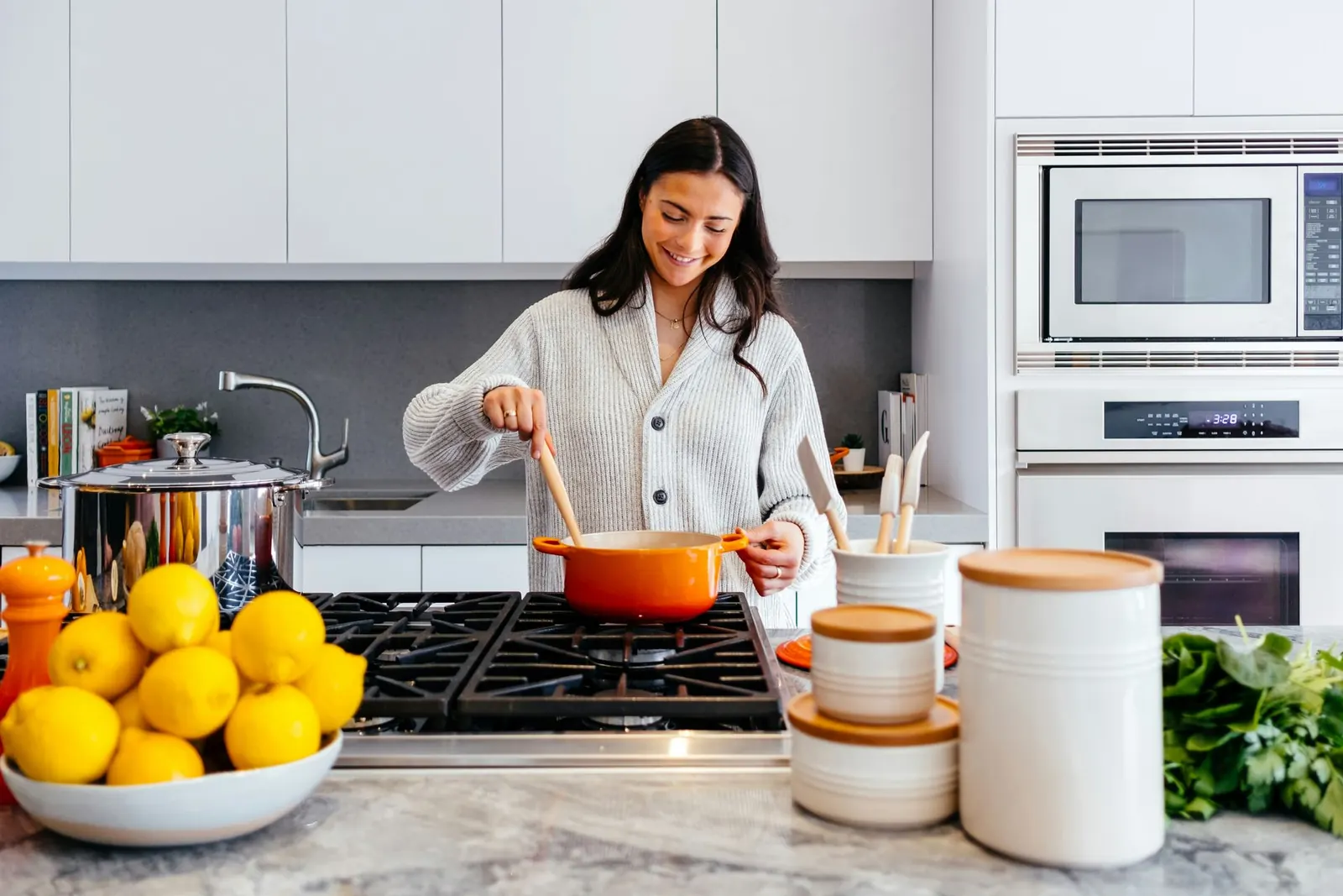 A woman cooking at a tidy kitchen counter with storage jars